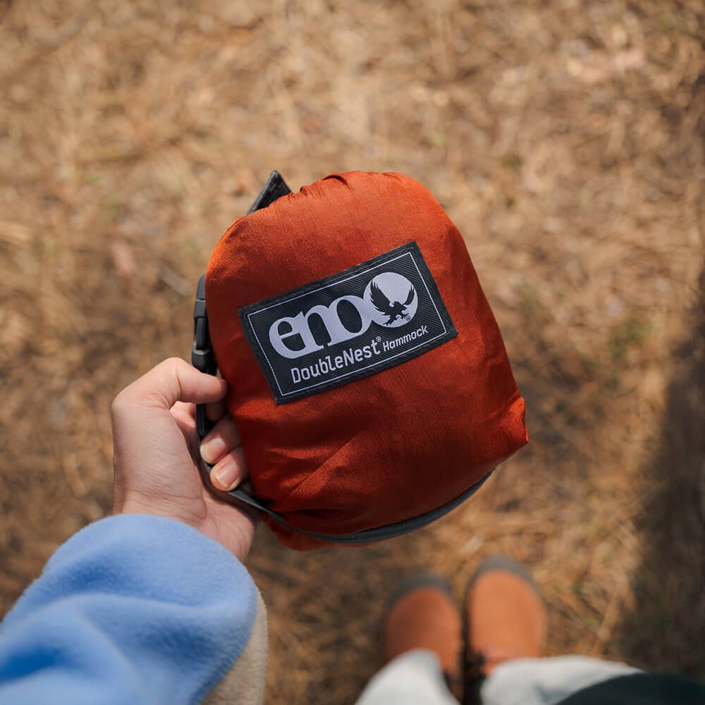 Packed up DoubleNest Hamock Stuff Sack with ENO logo held by a person outdoors